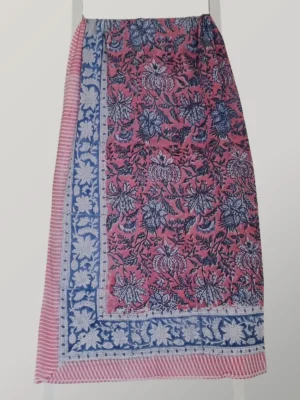 Berry Blue cotton sarong hanging full length, showing its raspberry pink florals framed by an indigo border